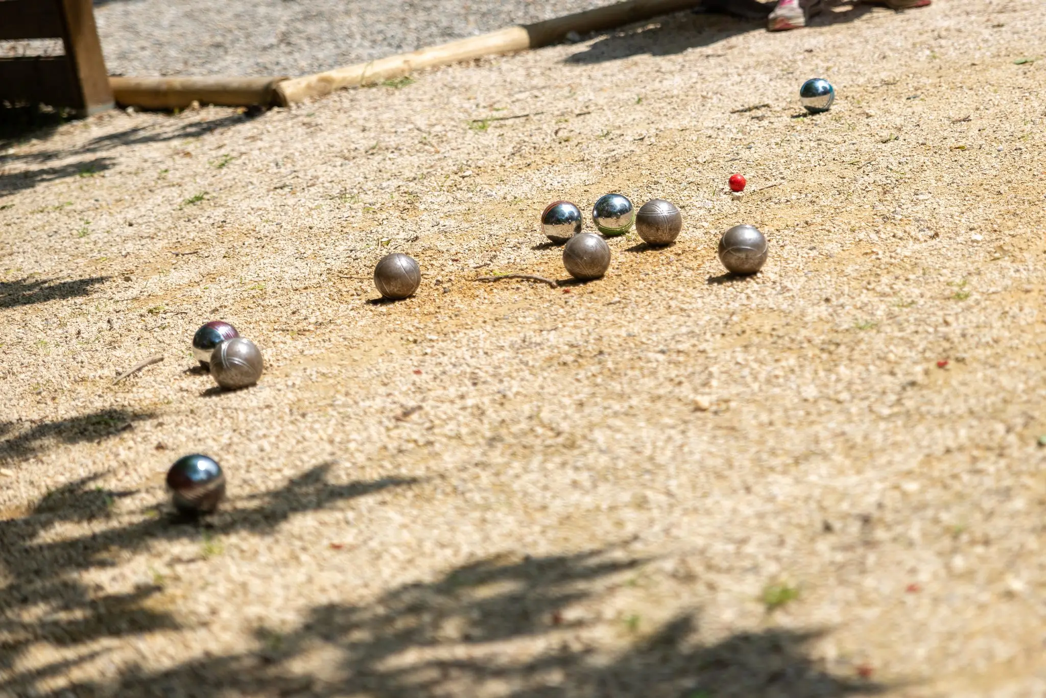 Boules de pétanque et cochonnet rouge sur un terrain sablé, faible profondeur de champ