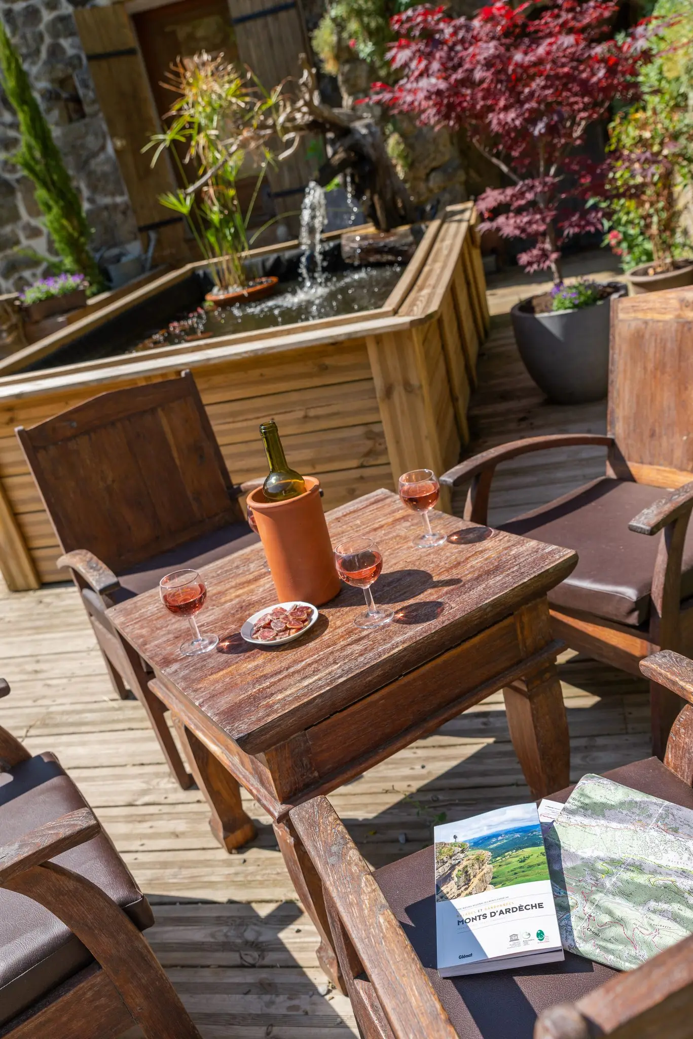 Table de terrasse en bois avec une bouteille de rosé et deux verres, au bord de la piscine