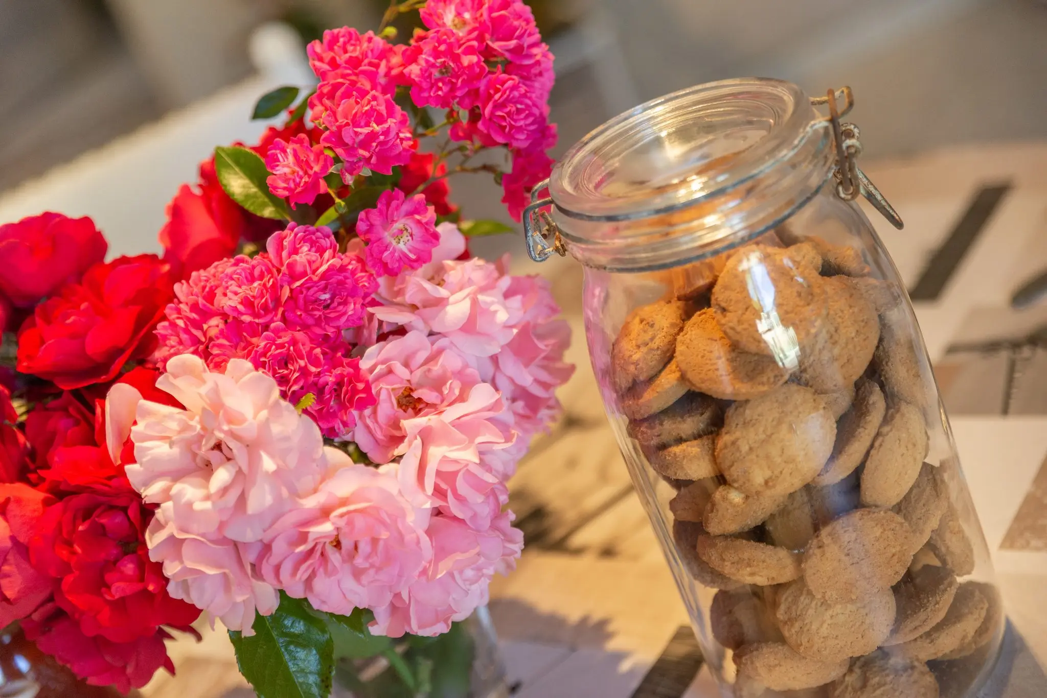 Bouquet de roses rouges et roses à côté d'un bocal de biscuits sur la table de la cuisine