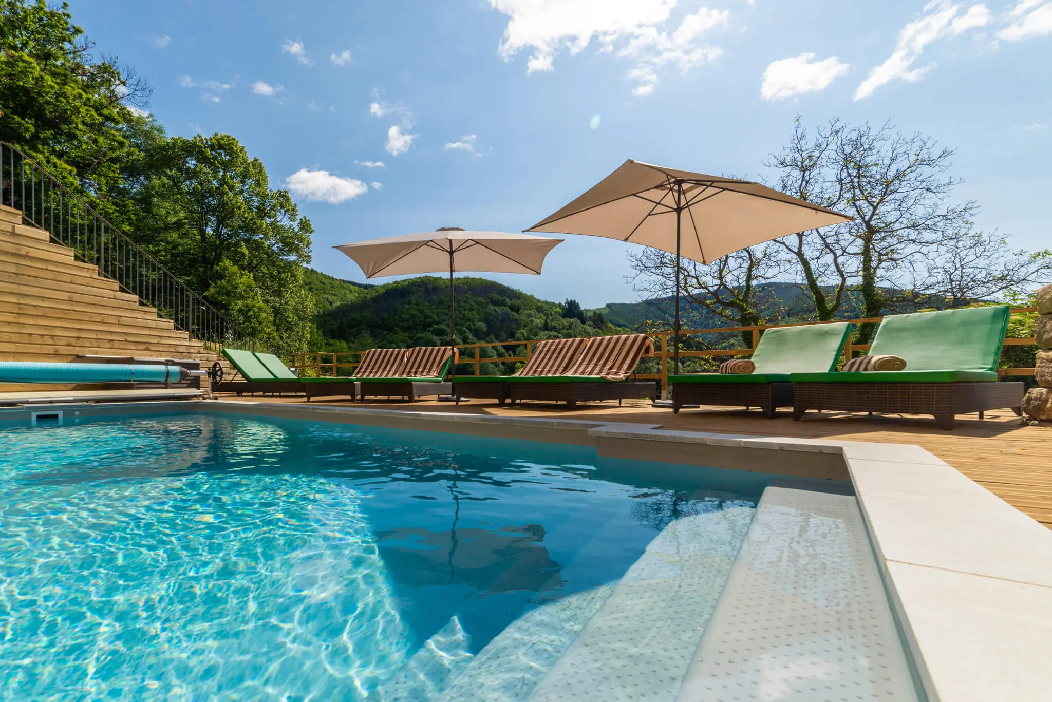 Piscine et terrasse en bois face aux collines boisées, chambres d’hôtes en Ardèche