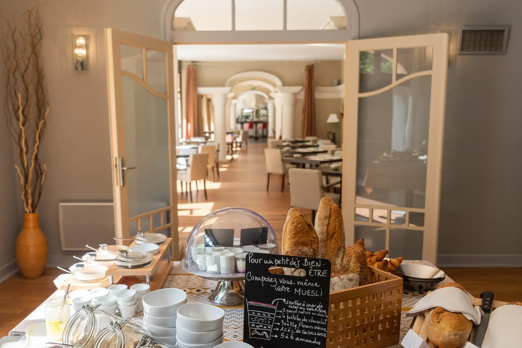Salle du petit-déjeuner d'un hôtel, buffet de pains et enfilade d'arcades blanches