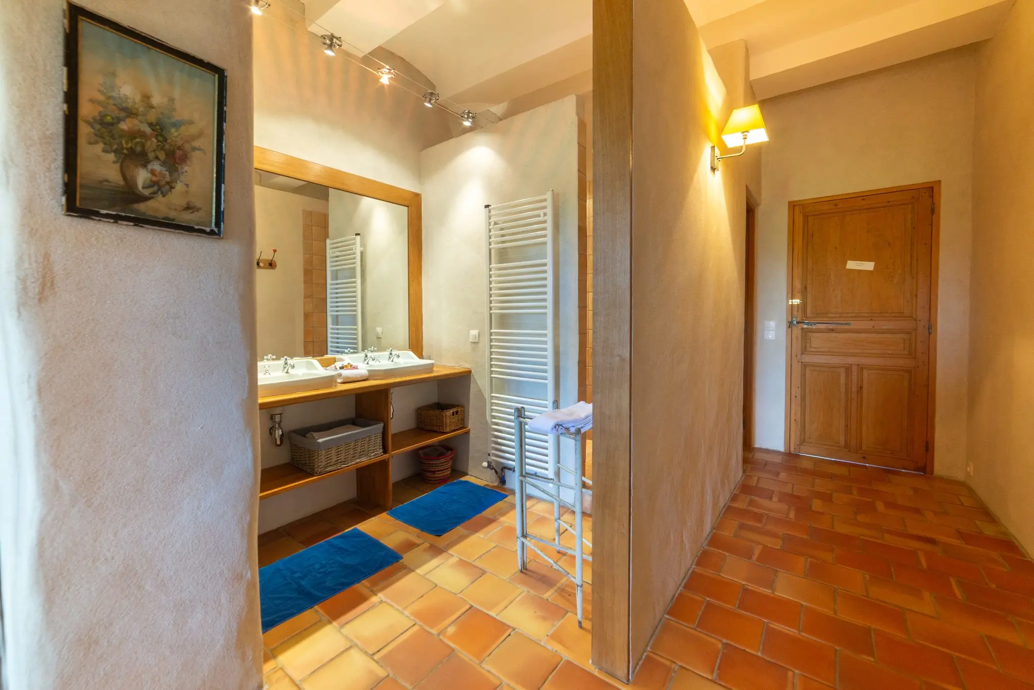 Salle d'eau d'une chambre d'hôtes, sol en tomettes, double vasque et porte en bois