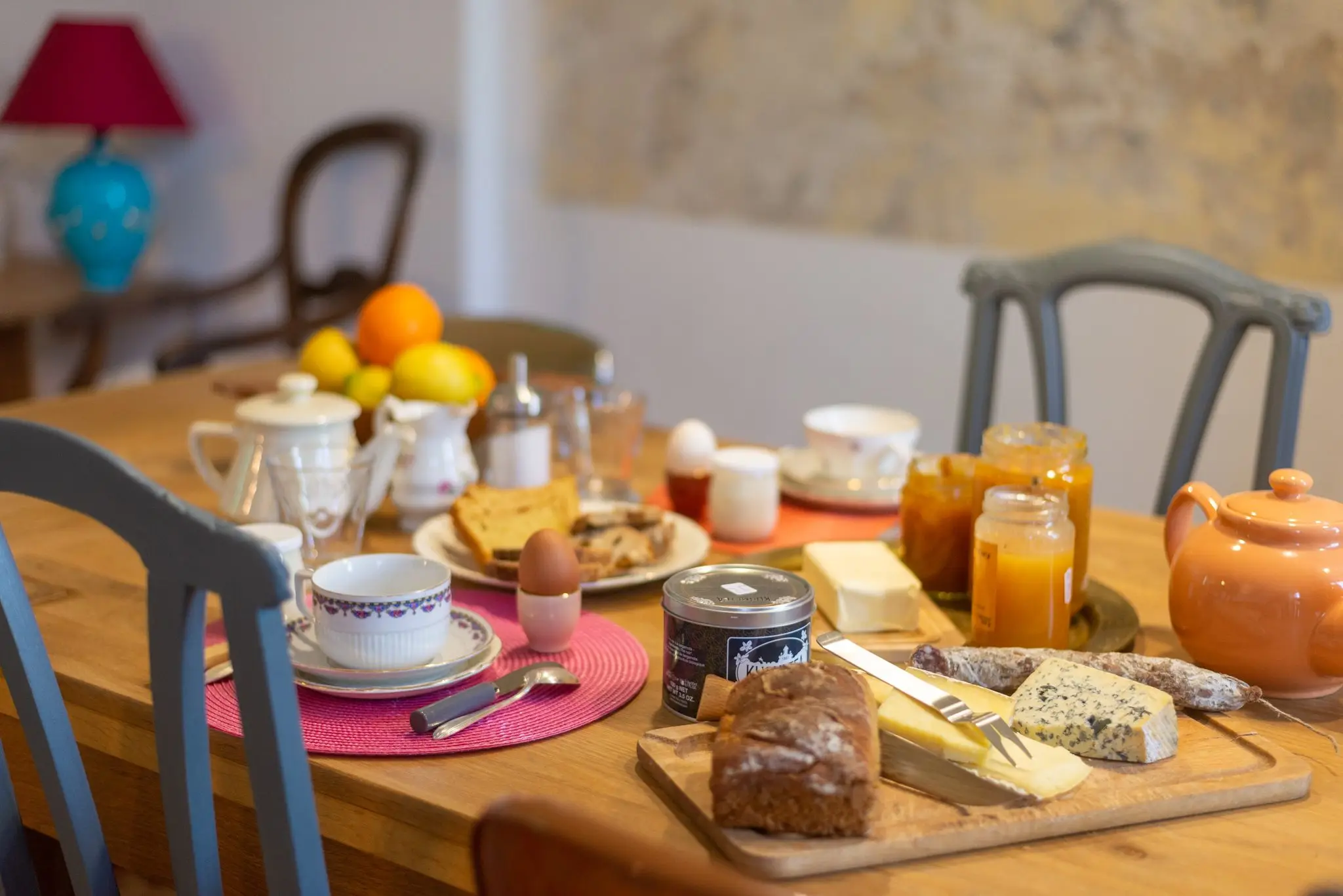 Table du petit-déjeuner dressée, théière, pain de campagne, fromage et confitures