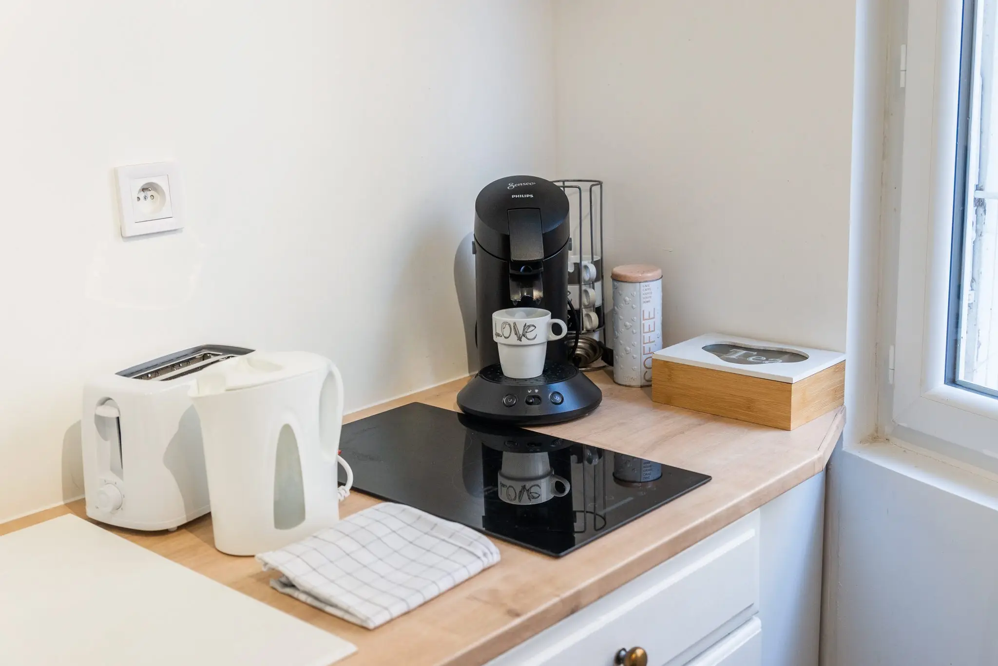 Plaque de cuisson, bouilloire, grille-pain et machine à café sur un plan de travail en bois clair
